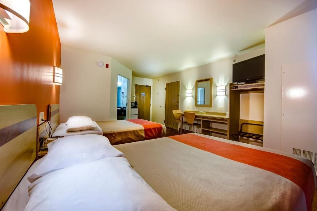 Une chambre d’hôtel avec deux lits, un bureau et un miroir.