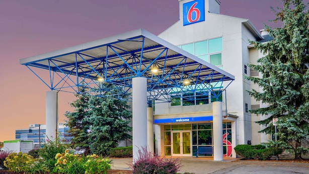 L’entrée d’un hôtel, avec un auvent bleu, un panneau indiquant le chiffre « 6 » et un panneau indiquant « bienvenue ».