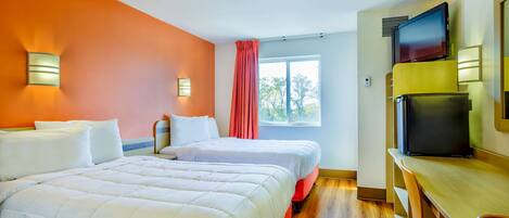 A hotel room with two beds, a desk with a chair, a television, and a window with curtains.