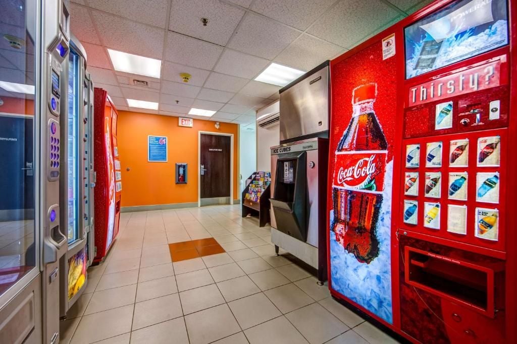 Un área de venta automática con varias máquinas, incluyendo una de Coca-Cola, y un congelador.