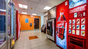 Un área de venta automática con varias máquinas, incluyendo una de Coca-Cola, y un congelador.