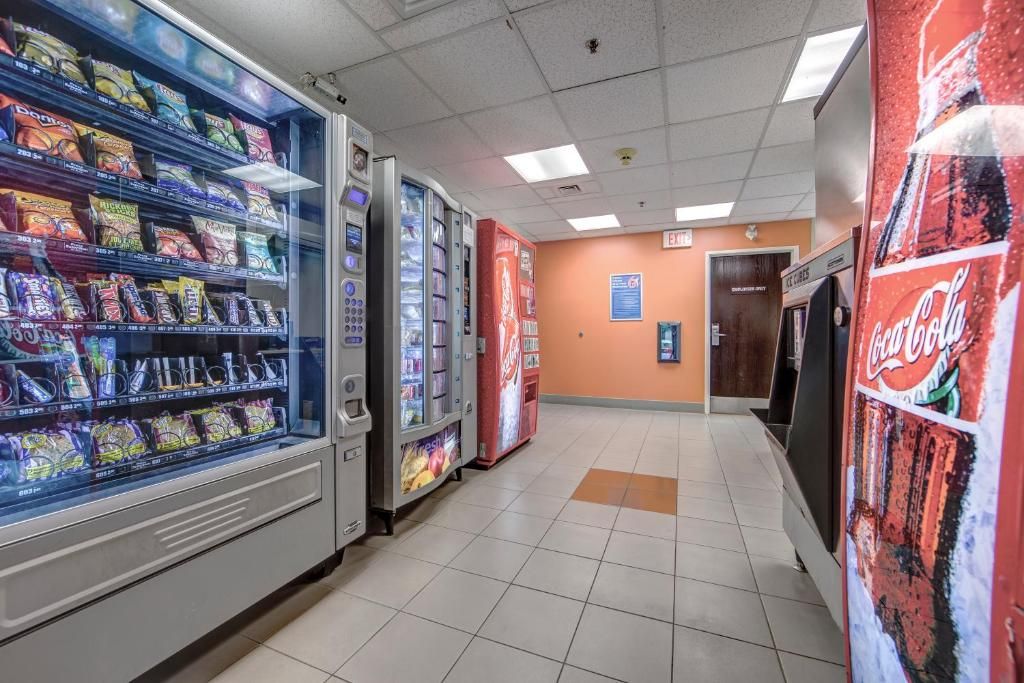 Un espace de vente proposant des distributeurs automatiques de collations et de boissons, ainsi qu’un distributeur de Coca-Cola et une affiche à l’effigie de la marque Coca-Cola.