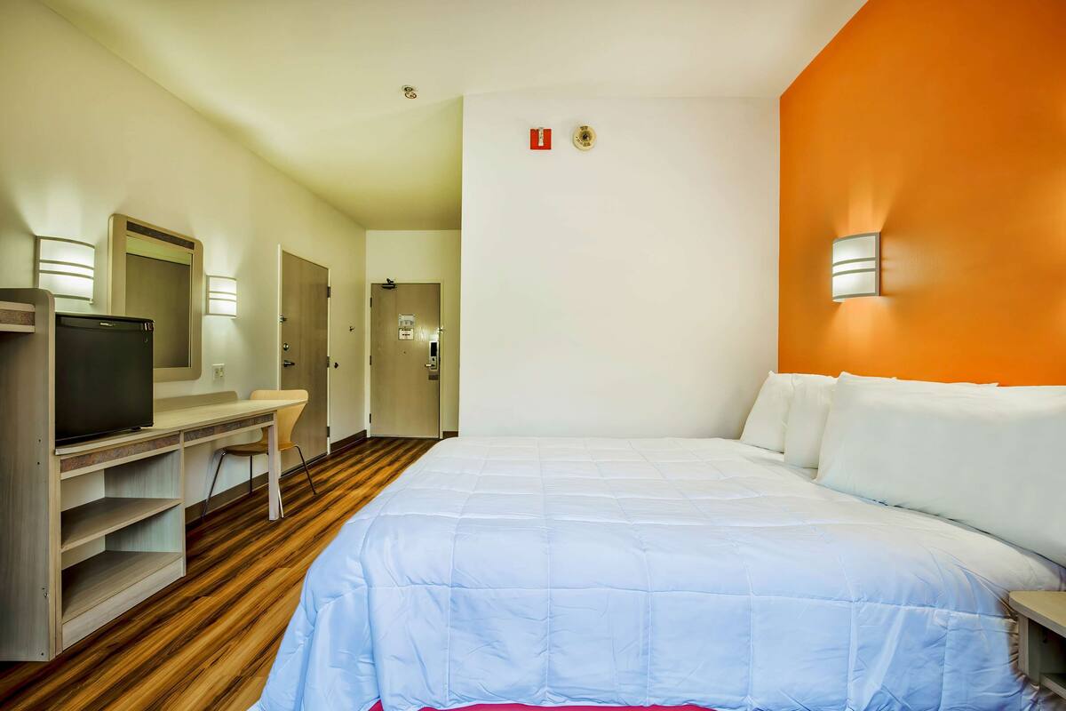 Une chambre d’hôtel équipée d’un lit, d’un bureau, d’une télévision et d’un miroir.