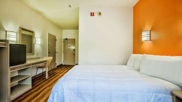 A hotel room with a bed, a desk, a television, and a mirror.