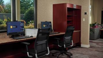 A workspace with two desks, each with a computer and keyboard, and two office chairs.