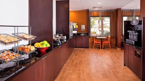 A hotel breakfast area with a buffet, a coffee machine, and a seating area with a table and chairs. - Fairfield Inn & Suites by Marriott Houston Hobby Airport. (Houston)
