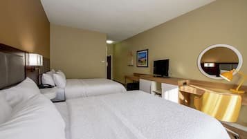 Habitación de hotel con dos camas, un escritorio, una silla, un televisor y un espejo.