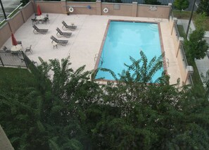 A rectangular pool with a tiled deck, surrounded by lounge chairs and umbrellas.