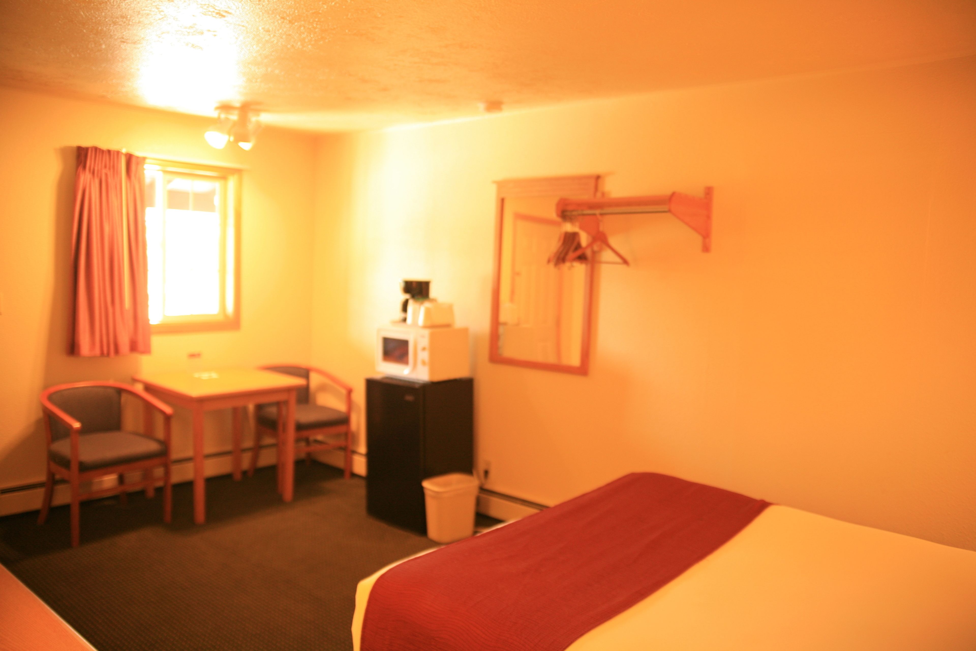 Een hotelkamer met een bed, een bureau met stoel, een magnetron en een kledingkast.