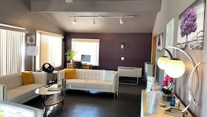 Uma sala de estar moderna com um sofá branco, uma mesa de centro de vidro e um espaço de jantar com mesa e cadeiras de madeira.