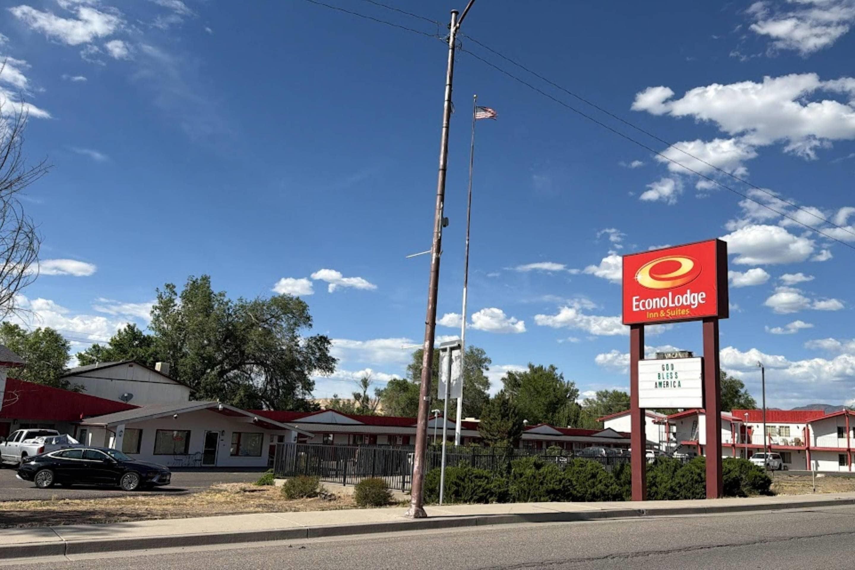 A motel with a prominent red sign, a flagpole with an American flag, and a building with a red roof.