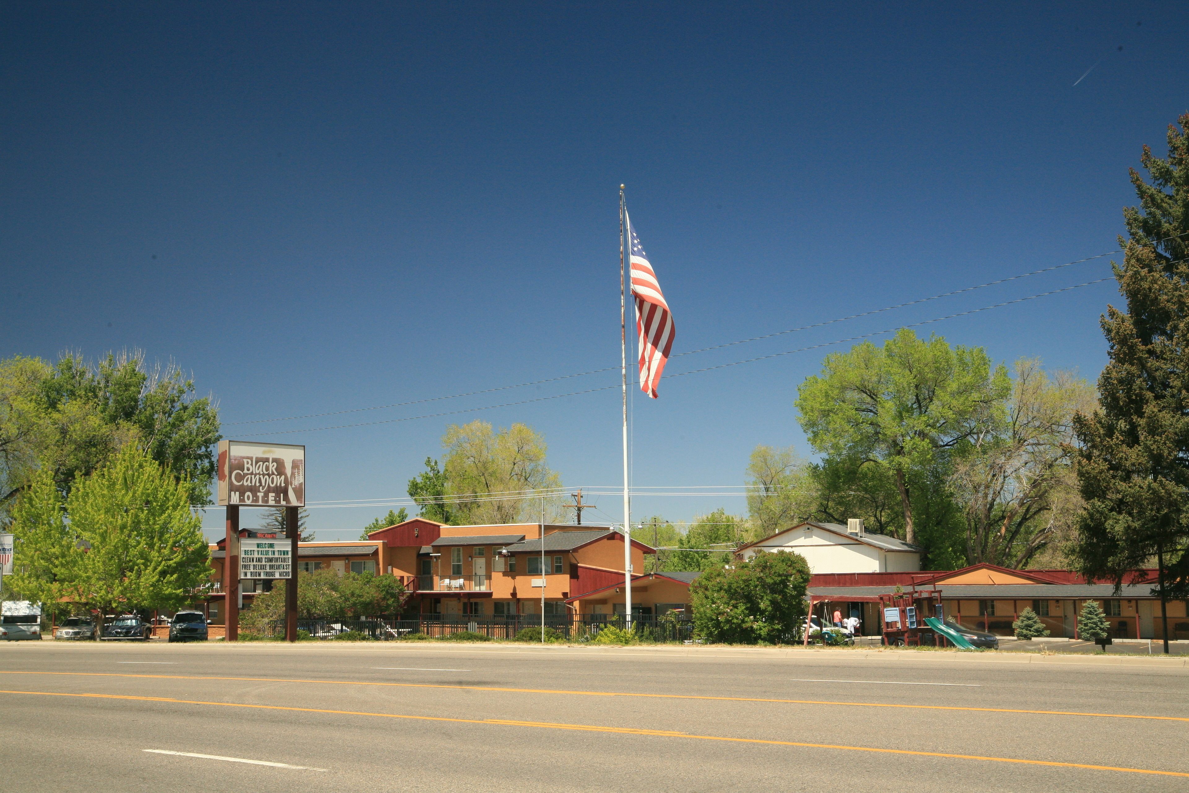 A motel with a flagpole, a signboard, and a playground.