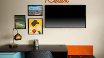 A modern room with a desk, a chair, a television, and artwork on the wall.