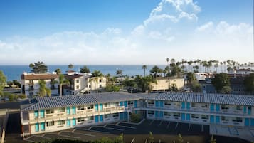 A motel with a parking lot and ocean view.