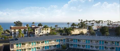 A motel with a parking lot and ocean view.