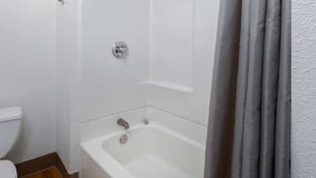 A bathroom with a white bathtub, a toilet, and a shower curtain.