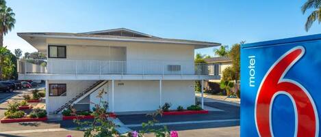 A motel with a two-story structure, a balcony, and a parking lot.