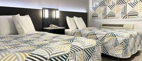 A hotel room with two beds, a bedside table with a phone, and a wall with a geometric pattern.