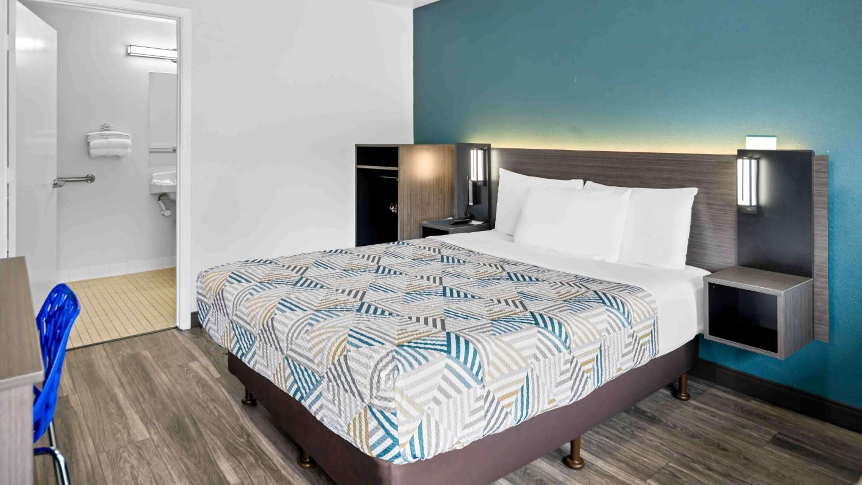 Una camera d'albergo con un letto, comodini, un armadio e un bagno.