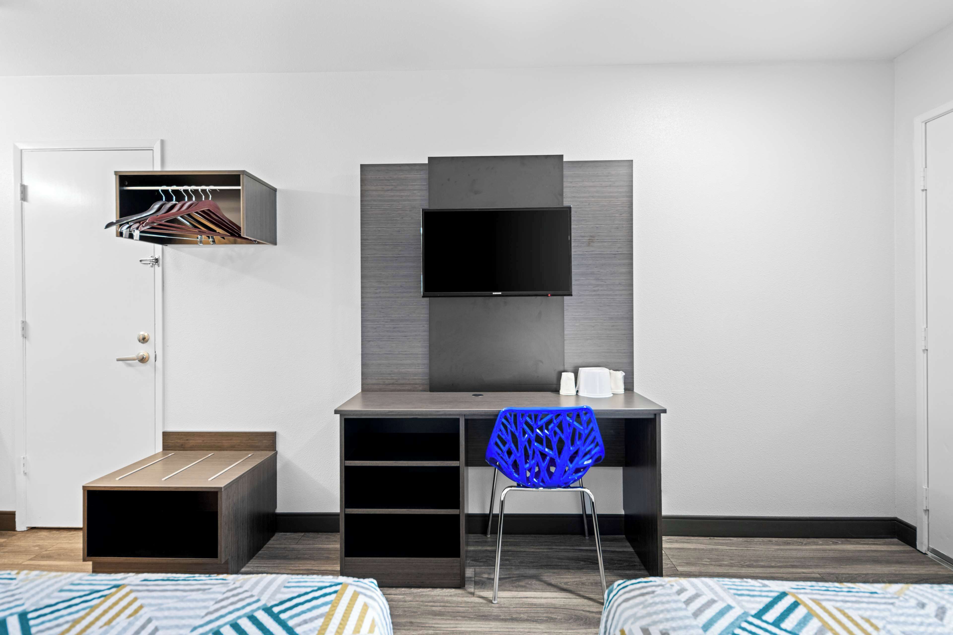Une chambre moderne équipée d’un bureau, d’une chaise, d’une télévision et d’une armoire.