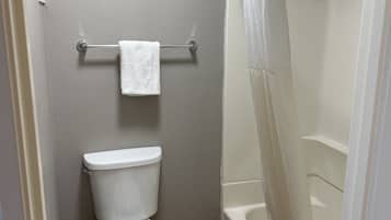 Un baño con inodoro, ducha con cortina y toallero.