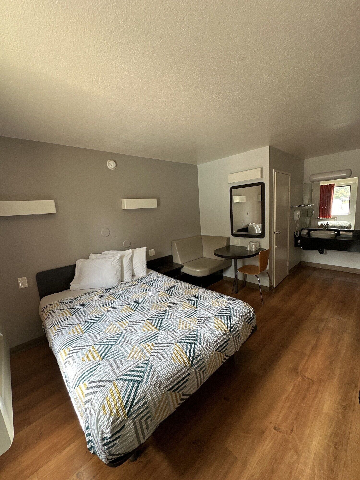 Una habitación de hotel con una cama, un escritorio, una silla y un baño.
