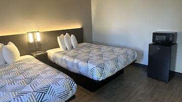 Une chambre d’hôtel moderne équipée de deux lits, d’un petit bureau et d’un four à micro-ondes.