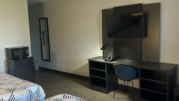A hotel room with two beds, a desk, a chair, a TV, and a microwave.