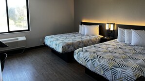 Una habitación de hotel con dos camas, una ventana, un calentador y una mesita de noche con una lámpara.