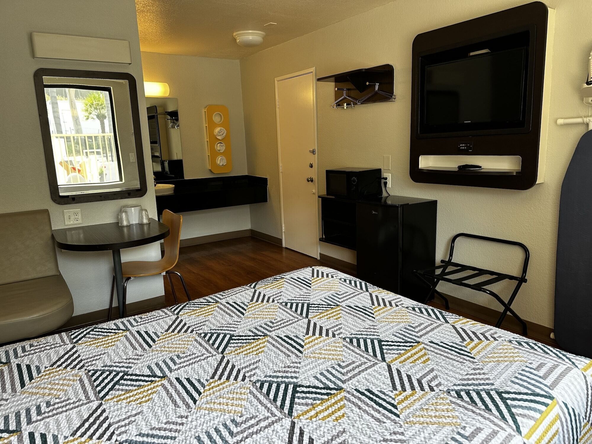 Habitación de hotel compacta con cama, un escritorio pequeño, una silla, televisión y ventana con vistas.