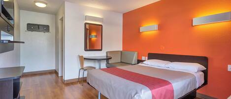 Una habitación de hotel con cama, escritorio, silla y una mesita.