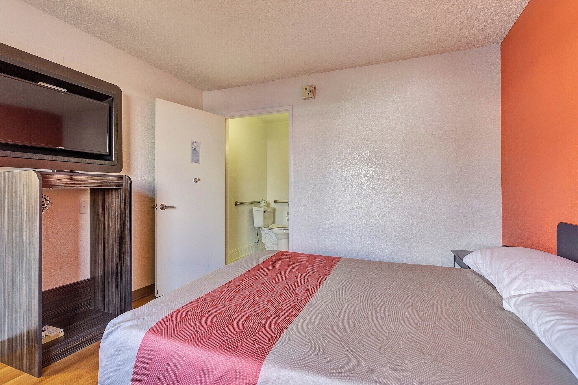 Een slaapkamer met een bed, een kledingkast en een badkamer, zichtbaar door een geopende deur.