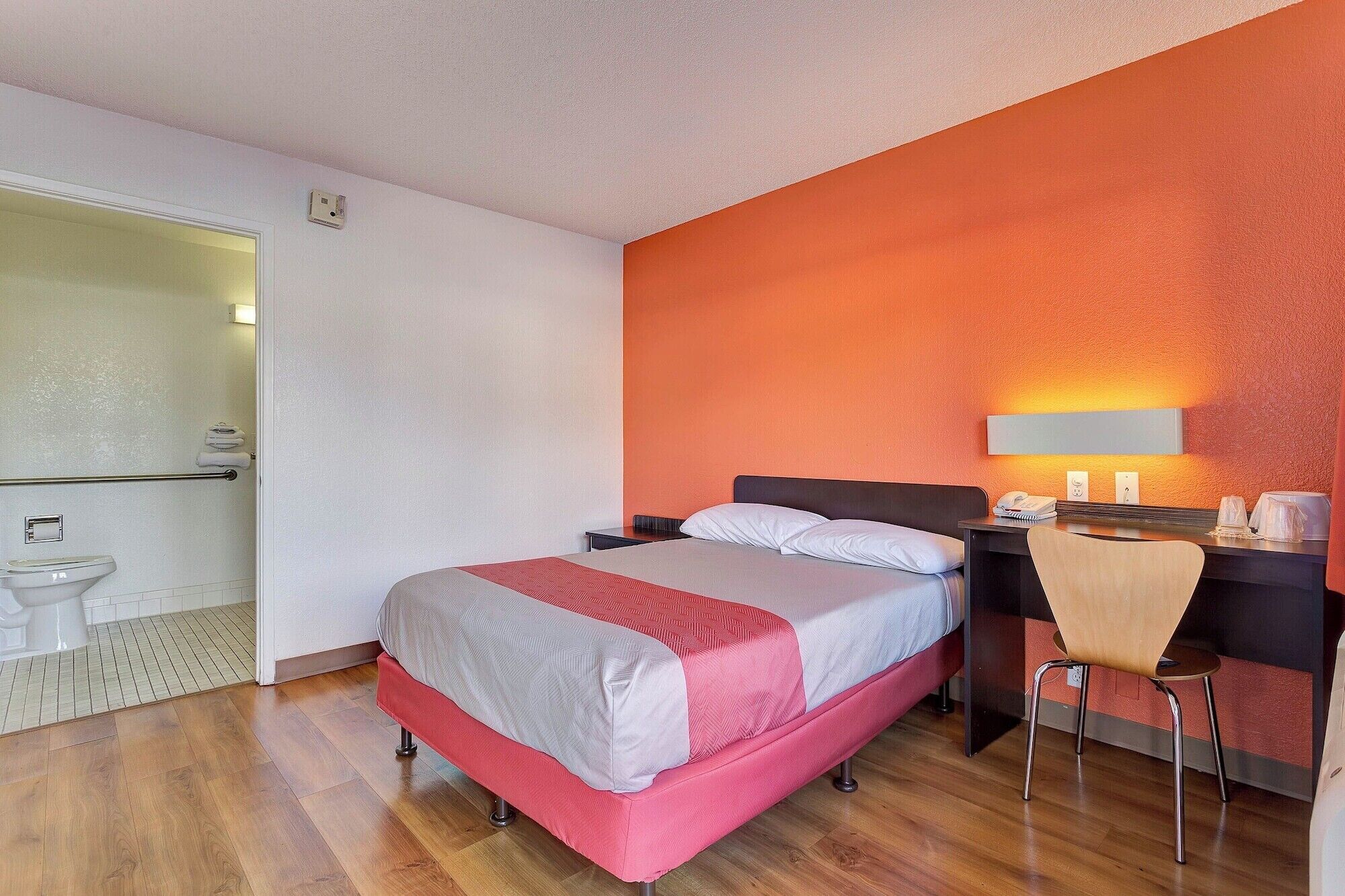 Une chambre d’hôtel avec un lit, un bureau, une chaise et une salle de bain.