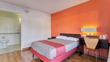 Une chambre d’hôtel avec un lit, un bureau, une chaise et une salle de bain.