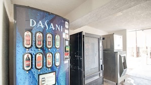 A vending machine with multiple beverage options and a push button for service. - Motel 6-Phoenix, AZ - East (Phoenix)