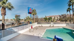 A motel with a pool area, including lounge chairs and a covered section. - Motel 6-Phoenix, AZ - East (Phoenix)