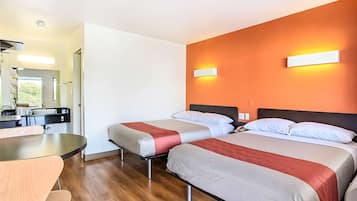 A hotel room with two beds, a dining table, and a kitchenette.