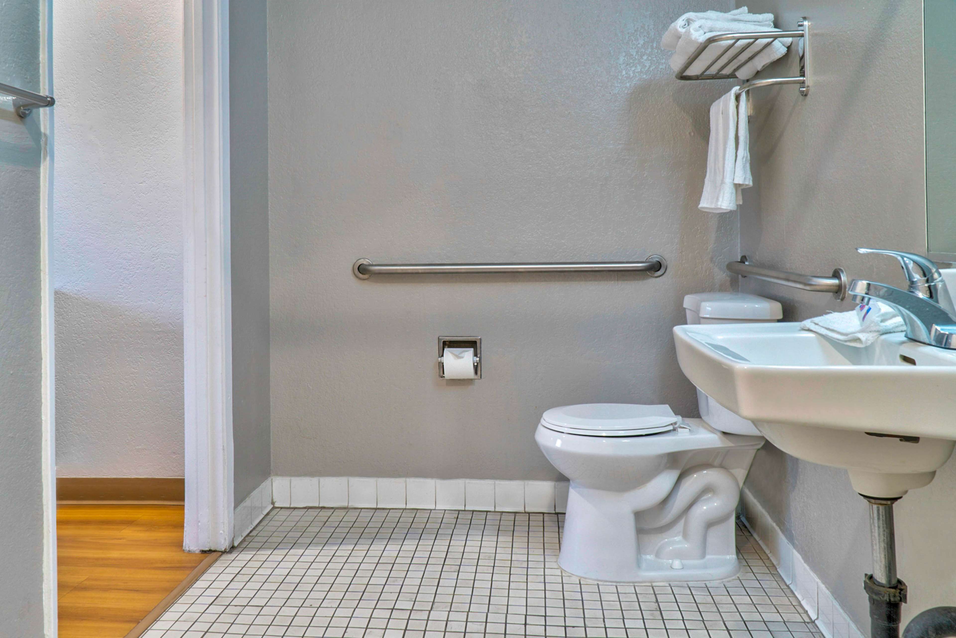 A bathroom with a toilet, a sink, a towel rack, and a grab bar.