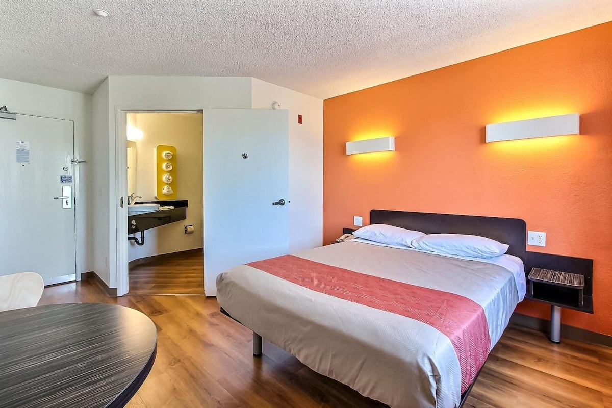 Una habitación de hotel con cama, mesita de noche y escritorio con silla.