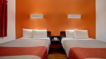 A hotel room with two beds, a wooden floor, and a red curtain.