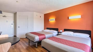 A hotel room with two beds, a desk, and a door.