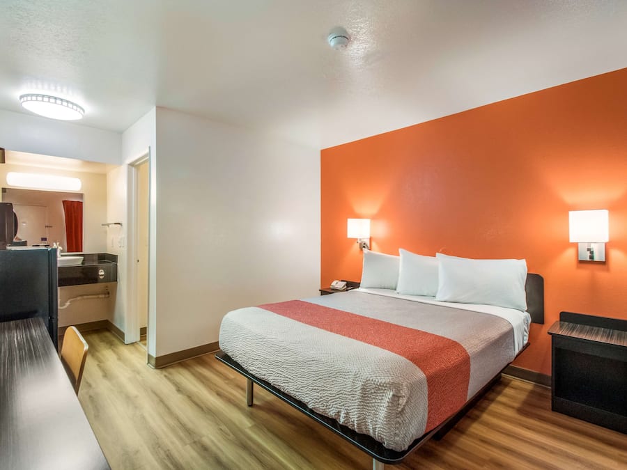 A hotel room with a bed, bedside tables, a desk, and a chair.