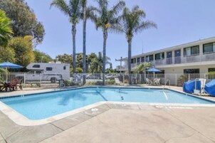 Una piscina al aire libre, sombrillas, sillones reclinables de piscina