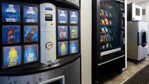 Ein Getränkeautomat mit verschiedenen Auswahlmöglichkeiten und eine Kühlvitrine mit Snacks.