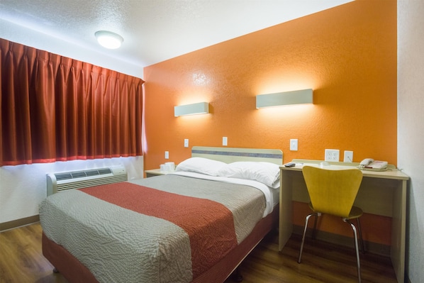 A hotel room with a bed, a desk with a chair, a telephone, and a window with curtains. - Motel 6 – Lakewood, CO (Lakewood)