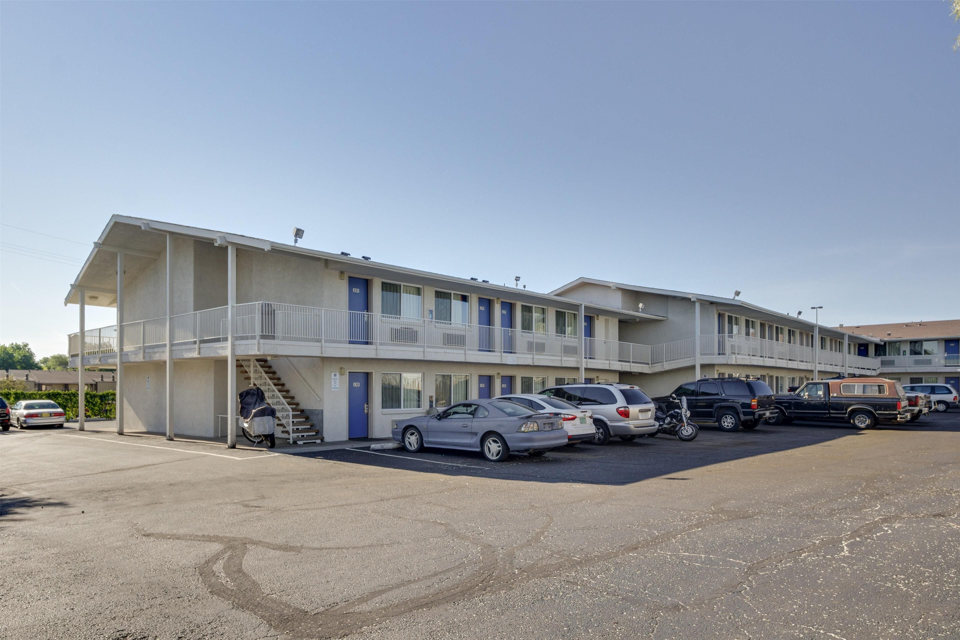 A motel with multiple floors, a parking lot, and several cars parked in front.