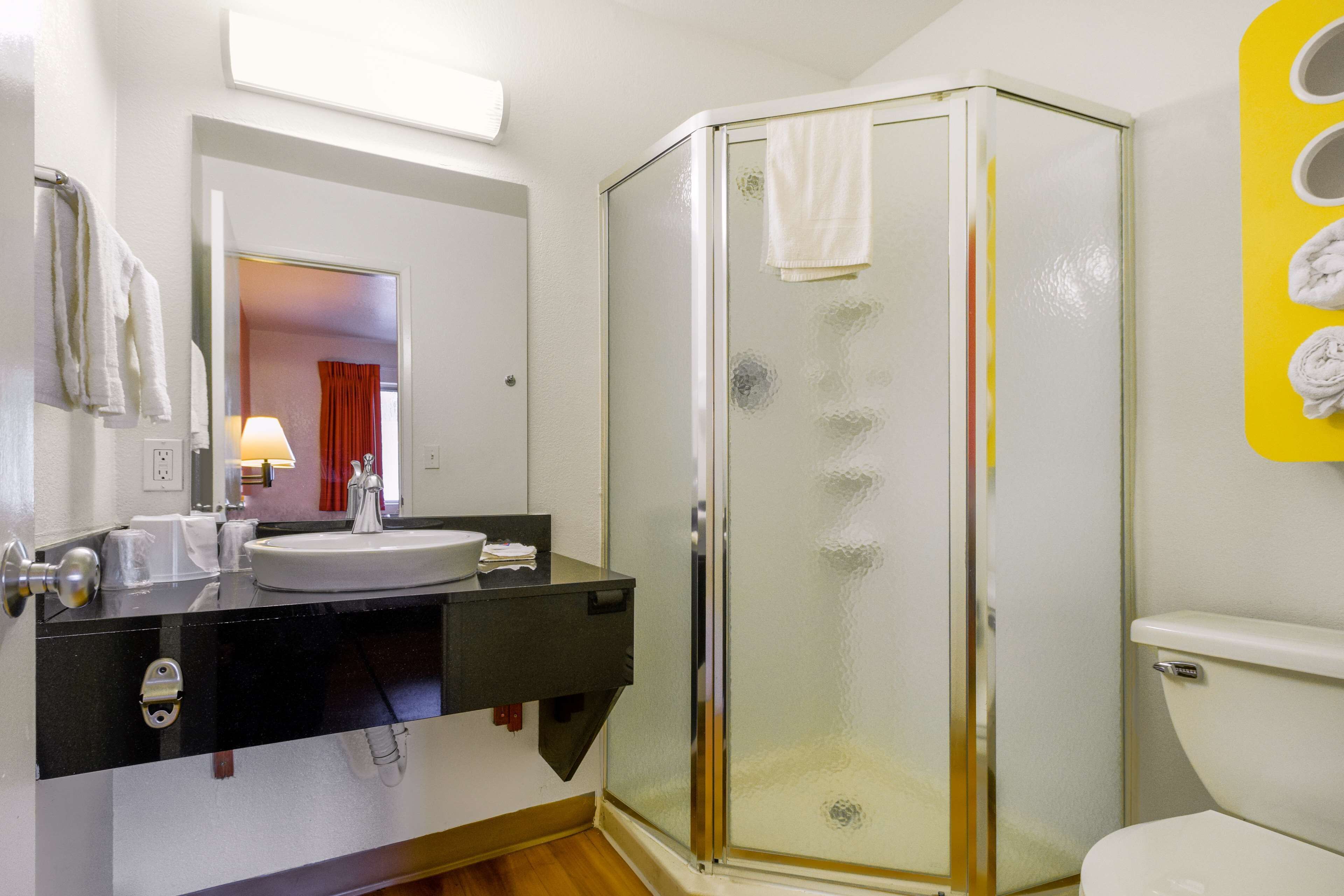 A bathroom with a glass-enclosed shower, a sink, and a toilet.