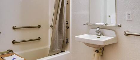 A bathroom with a bathtub, a sink, and a mirror.
