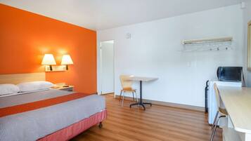 Habitación de hotel con cama, escritorio y silla. Hay dos lámparas fijadas a la pared junto a la cama.