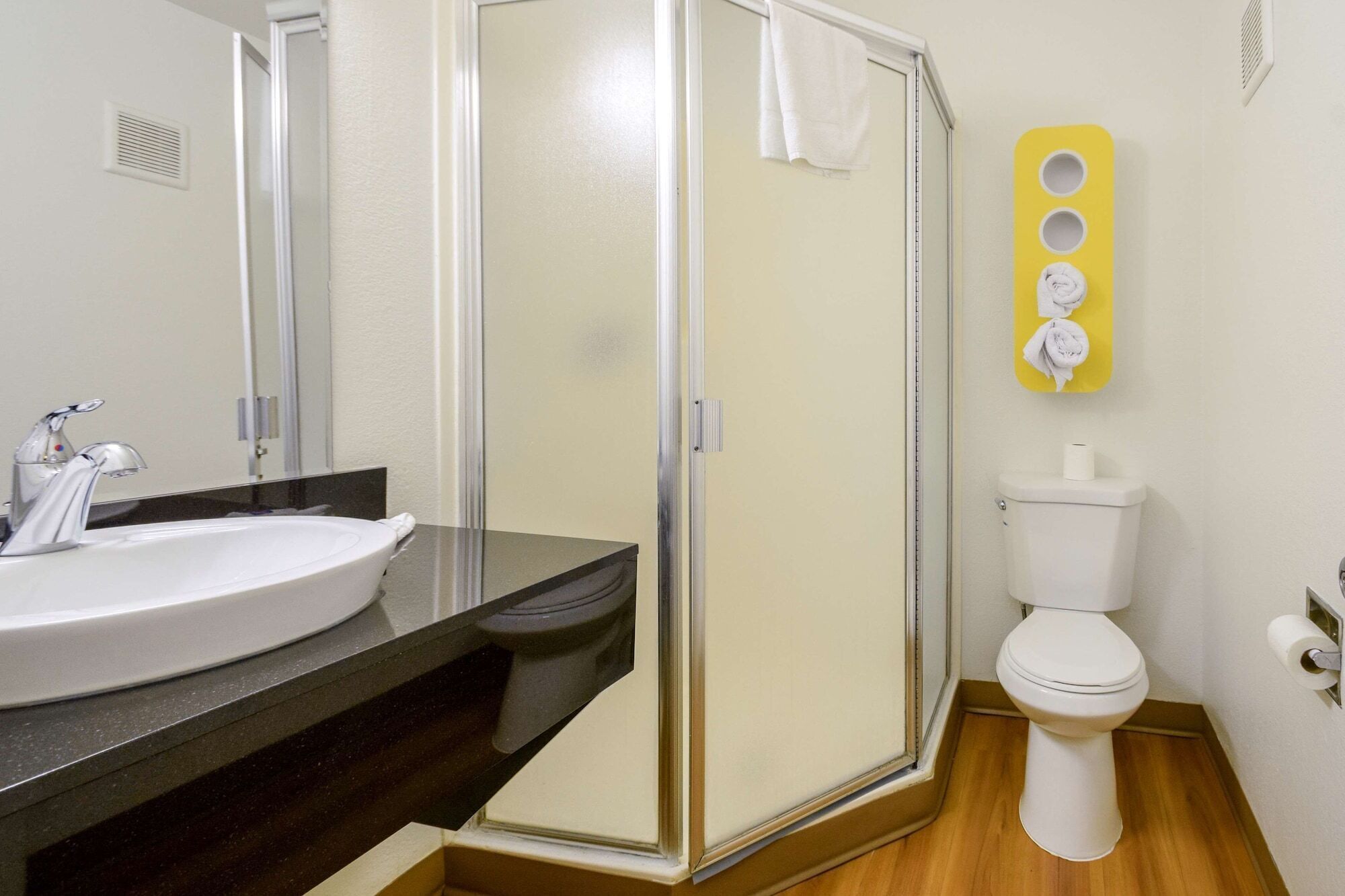 A bathroom with a glass-enclosed shower, a white sink, and a toilet.